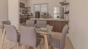 A modern kitchen with a glass dining table and four chairs, a refrigerator, and a coffee maker. - New Merida Retreat with Private Pool (Mérida)