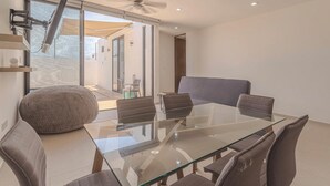 A modern dining area with a glass table and six chairs, a large bean bag, and a ceiling fan. - New Merida Retreat with Private Pool (Mérida)