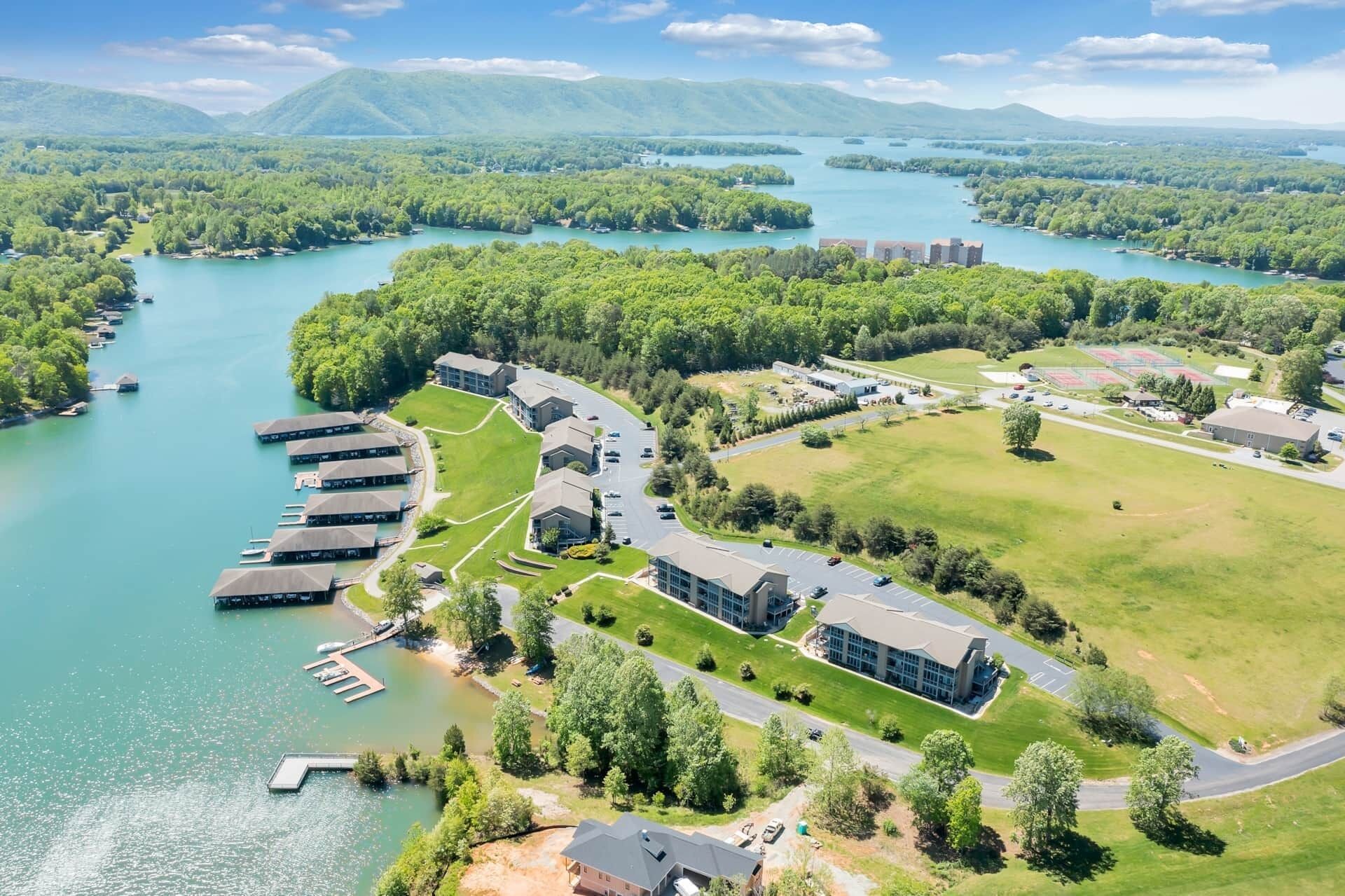 An aerial view of a resort with a marina, buildings, and a lake surrounded by greenery.