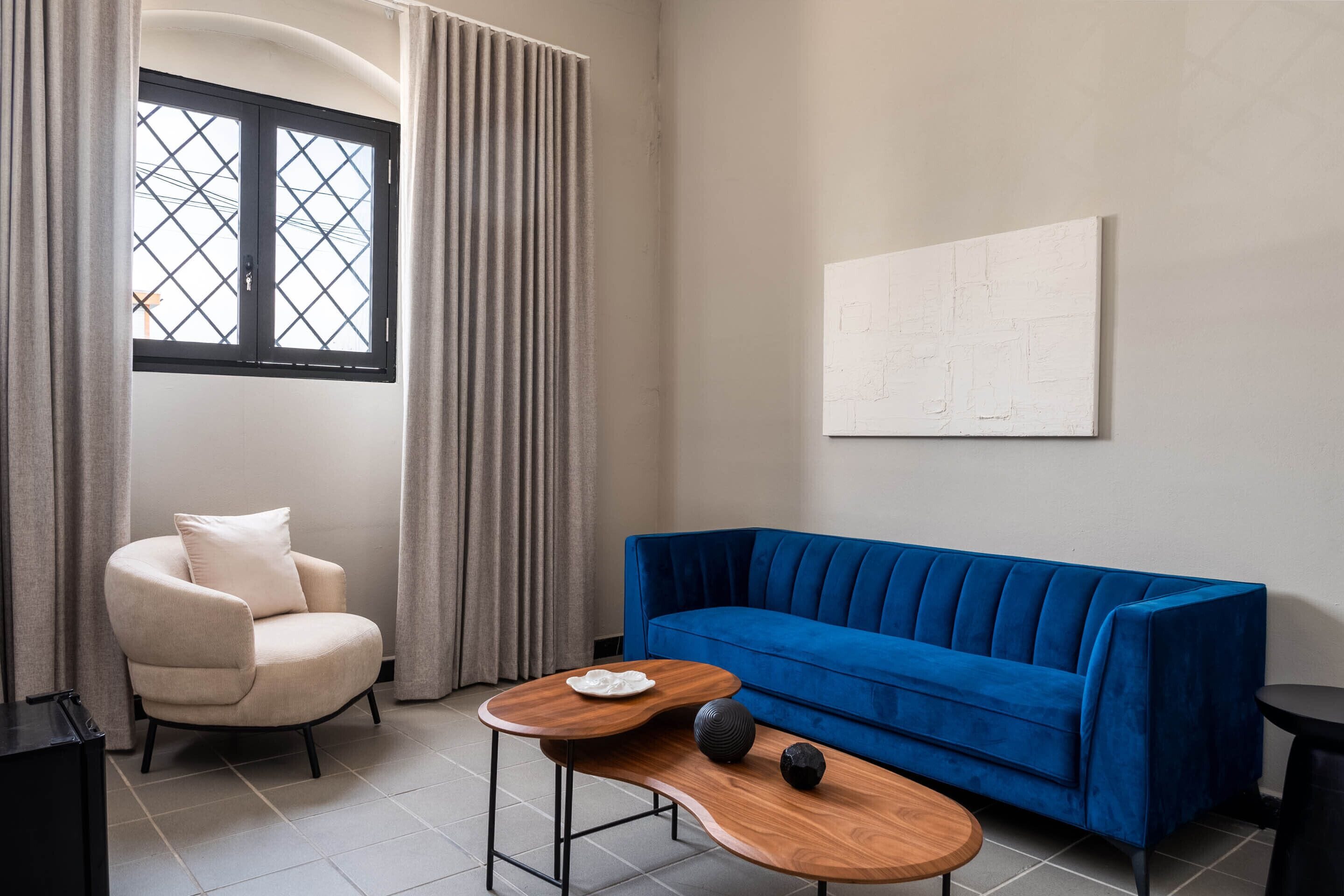 Een moderne woonkamer met een blauwe bank, een witte fauteuil en een houten salontafel.