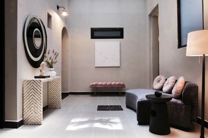 Una sala de estar moderna con un sofá, un banco, una mesa y un televisor montado en la pared.