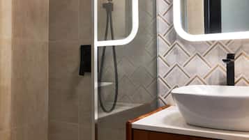 Une salle de bain avec un lavabo blanc, un miroir et une douche.