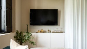 A living room with a flat-screen TV mounted on the wall, a white cabinet below, and a green sofa with a white cushion. - The Oliver Hotel - Adults Only (San Juan)