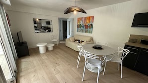A modern living room with a round dining table, white chairs, a beige sofa, and a painting on the wall. - Pornichet - Apartment near Hippodrome (PORNICHET)
