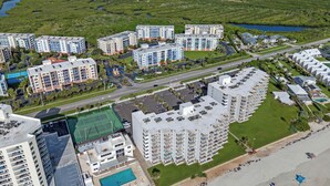 Een hoog hotel met meerdere verdiepingen, een zwembad en een strandgedeelte.