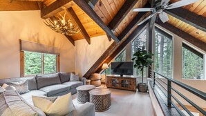 Een moderne woonkamer met een grote hoekbank, een flatscreen televisie en een plafondventilator.