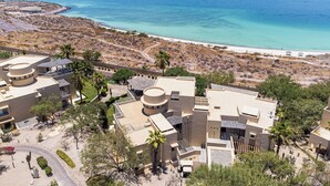 A coastal resort with multiple buildings, a beach, and a view of the sea.