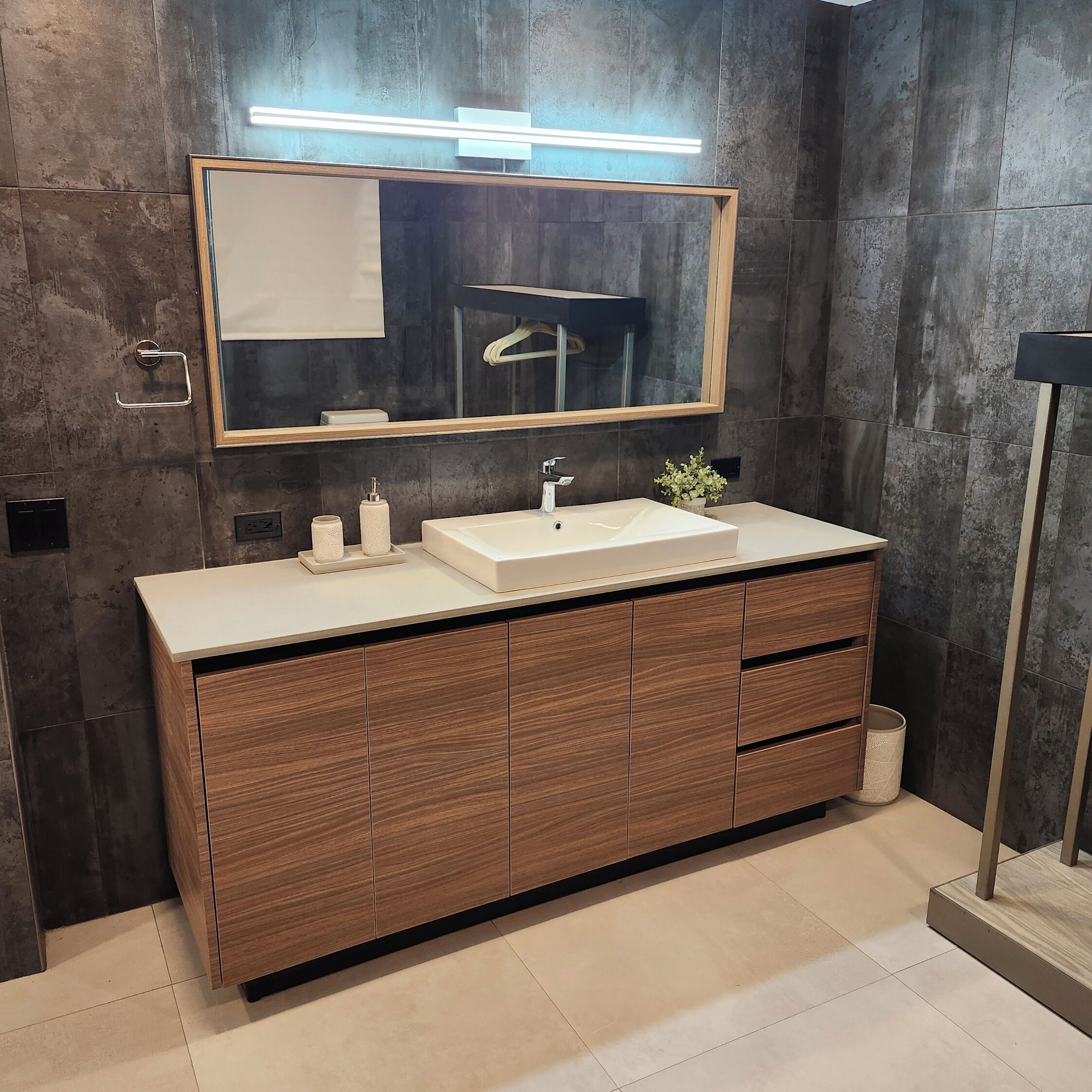 A modern bathroom with a large mirror, a sink, and wooden cabinets.