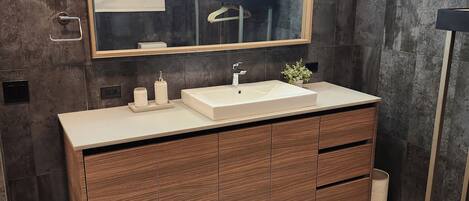 A modern bathroom with a large mirror, a sink, and wooden cabinets.