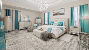 Quarto moderno com uma cama grande, cômoda, penteadeira e um candelabro.