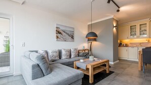 A modern living room with a grey sectional sofa, a wooden coffee table, and a pendant lamp.