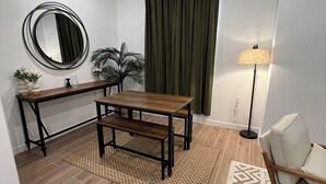 Een moderne woonkamer met een houten eettafel, een plafondventilator, een vloerlamp en een kamerkleed met dessin.