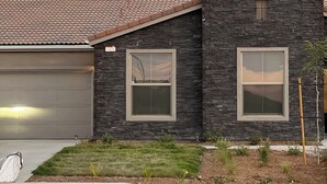 Een modern herenhuis met twee verdiepingen, een stenen gevel, een garage en een verzorgde voortuin.