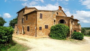 A historic stone building with multiple windows and a central arched doorway, surrounded by greenery. - GuestHost - Elegant 85 sqm apartment in a renovated farmhouse in Castiglione del Lago, Umbria. Ideal for 4 people, it offers a communal pool, a reserved outdoor parking space for guests, and a private garden. Surrounded by nature, it is perfect for those (Castiglione del Lago)