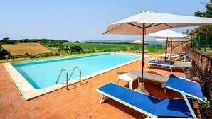 A swimming pool with a view of the countryside, outdoor seating, and umbrellas. - GuestHost - Elegant 85 sqm apartment in a renovated farmhouse in Castiglione del Lago, Umbria. Ideal for 4 people, it offers a communal pool, a reserved outdoor parking space for guests, and a private garden. Surrounded by nature, it is perfect for those (Castiglione del Lago)