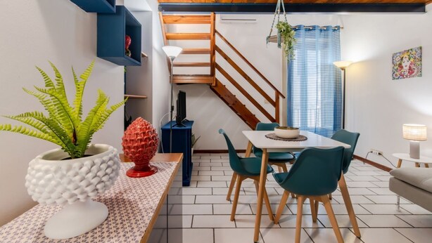 Een eetgedeelte met een tafel, stoelen, een potplant en een trap.
