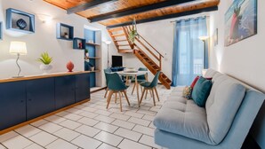 Een moderne leefruimte met een houten plafond, een eethoek met stoelen, een bank en een trap.
