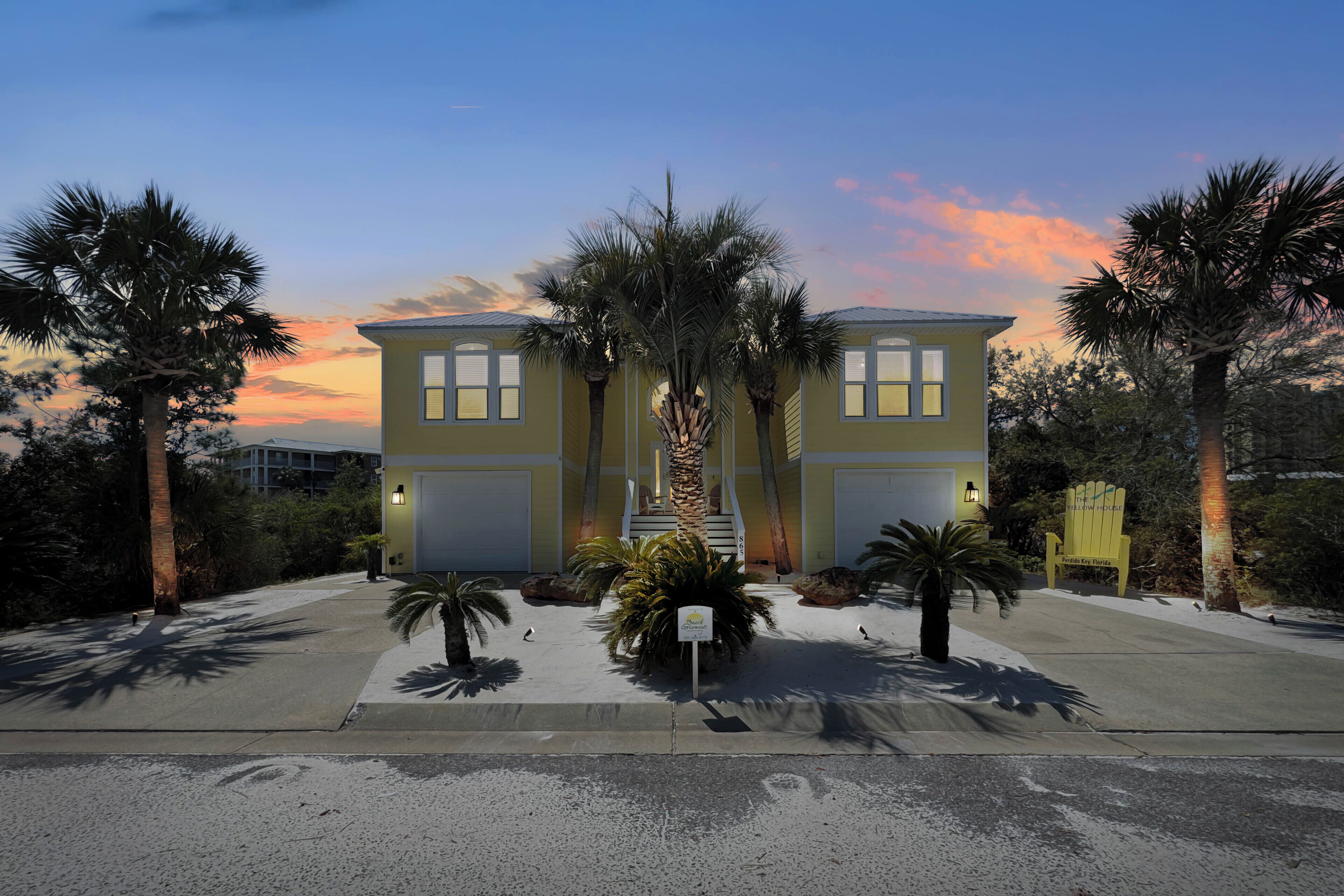 A two-story building with a symmetrical facade, a central staircase, and palm trees in the foreground.