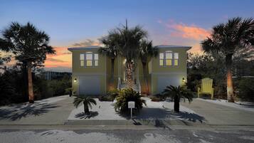 A two-story building with a symmetrical facade, a central staircase, and palm trees in the foreground.