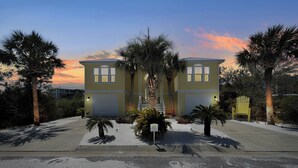 A two-story building with a symmetrical facade, a central staircase, and palm trees in the foreground.