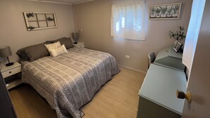 A bedroom with a bed, bedside tables, a desk, and a chair.