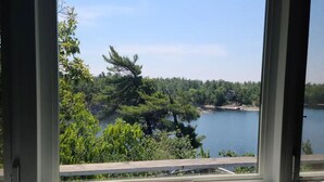 A view from a window with a sign reading "LAKE" and a glimpse of a lake surrounded by trees. - Feathery Pines cottage with sauna and sunset views (Nobel)
