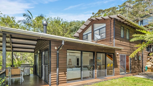 A modern house with a covered patio, large sliding glass doors, and a satellite dish.