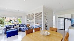 A modern living room with a sofa, ottoman, and dining table.