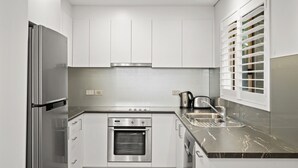 Eine moderne Küche mit Edelstahlgeräten, einem Backofen und einem Fenster mit Jalousien.