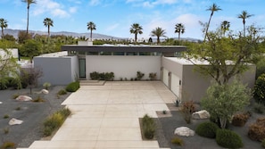 Un edificio moderno con tetto piatto, immerso in un giardino curato con diverse piante e rocce.