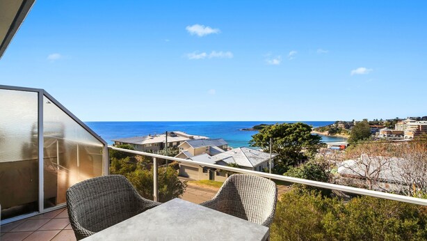 Un balcon avec vue sur la mer et les bâtiments environnants.