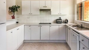 A kitchen with white cabinets, a toaster, and a kettle on the countertop.