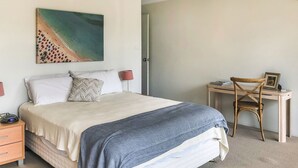 A bedroom with a bed, bedside tables, a desk, and a chair.
