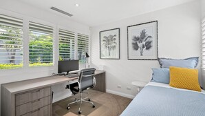 A modern bedroom with a desk, a bed, and two framed pictures on the wall. - Avoca Views (Avoca Beach)