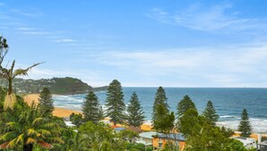 A coastal view with a beach, ocean, and residential area. - Avoca Views (Avoca Beach)