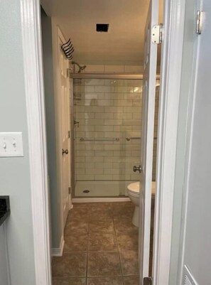 Enter a bathroom with a glass-enclosed shower and toilet.