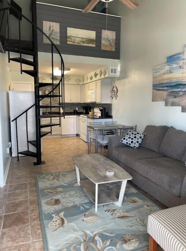 Relax in a stylish living space with a cozy seating area, spiral staircase, and a kitchen area with dining table.