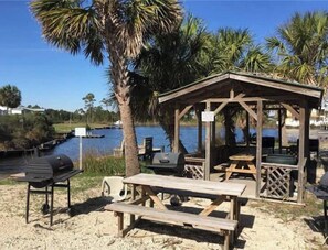 Relax in a serene outdoor setting with a shaded gazebo, barbecue grill, and picnic table.