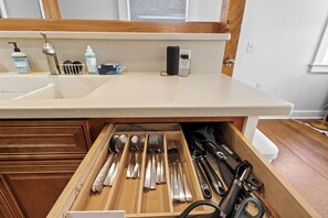 A kitchen with a countertop, a drawer with utensils, and a window above the sink.
