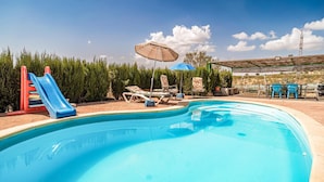 Piscina com escorregador, espreguiçadeiras e guarda-sóis.