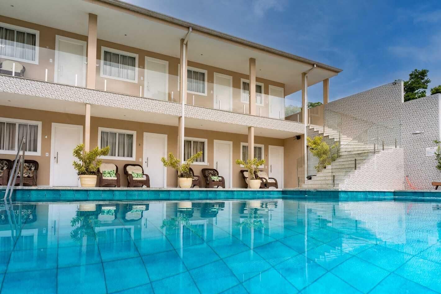 Ein Hotel mit Schwimmbad, mehreren Balkonen und Topfpflanzen.
