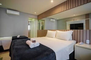 A hotel room with a large bed, a bedside table, a TV, and a mirror.