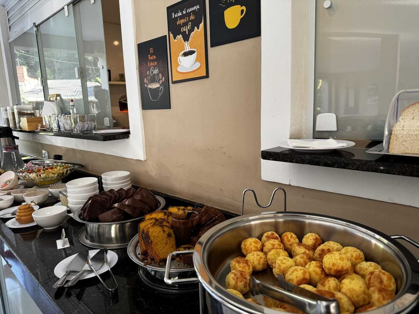 A buffet area with various food items, including a large bowl of breaded items, a tray of chocolate desserts, and a container of small fried balls.