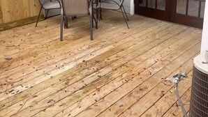 A covered patio area with a wooden deck, a round table, and four chairs. - End unit townhome with side yard (Baton Rouge)