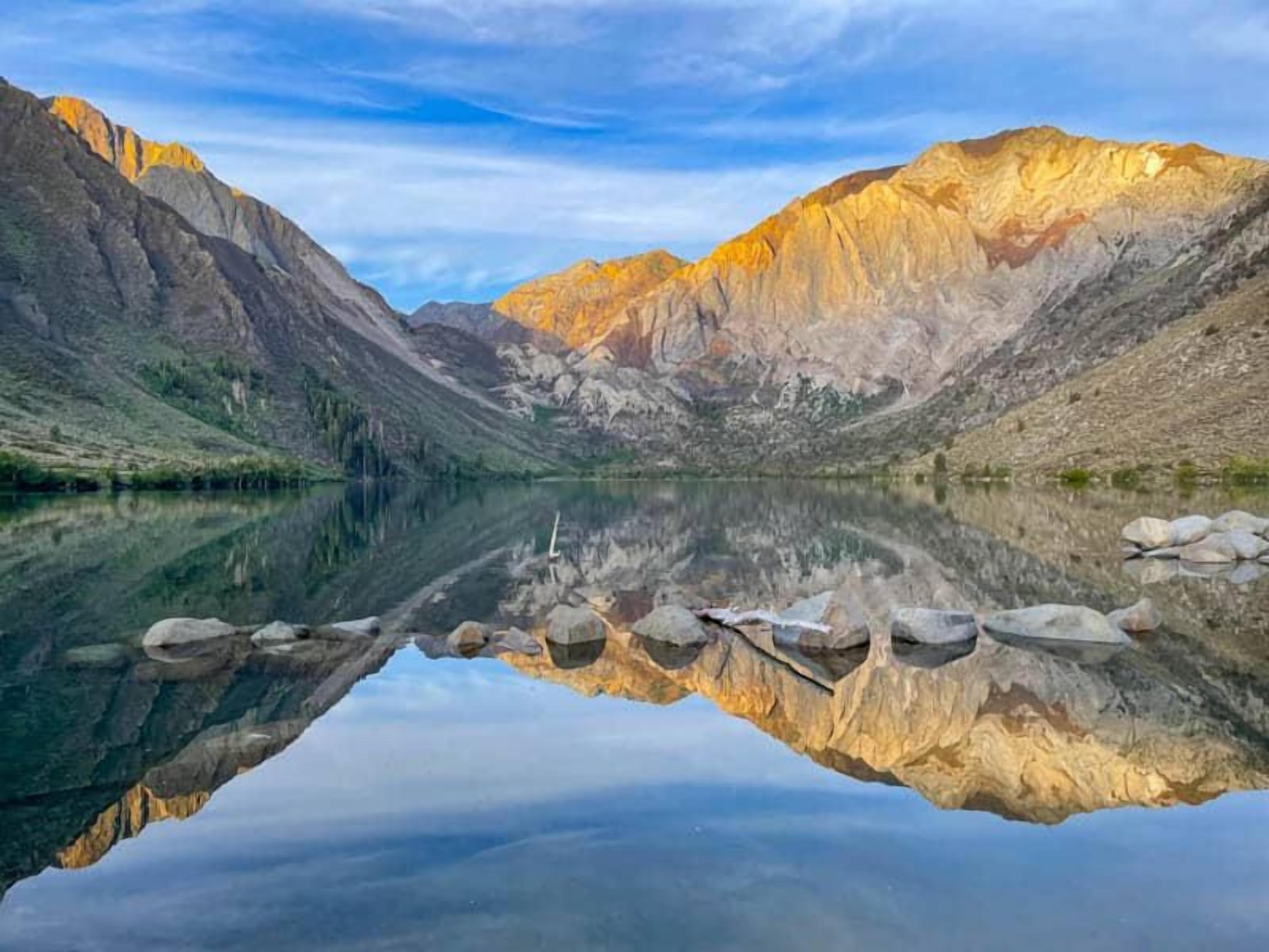 Paisaje montañoso con un lago tranquilo que refleja las montañas.