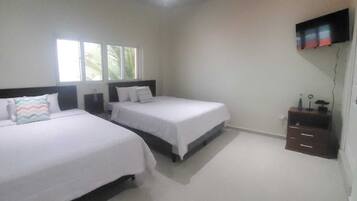 A bedroom with two beds, a TV mounted on the wall, and a small cabinet.