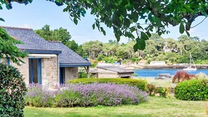 A stone house with a blue door and a sloped roof, surrounded by a well-maintained garden with lavender bushes. - La petite Pen Er Hoët by Interhome (La Trinité Sur Mer)