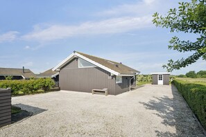 Een gebouw met een grindpad, een klein houten bankje en het nummer '35' op de muur.