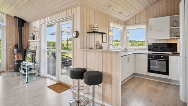 Una cocina moderna con paneles de madera, estufa integrada y un amplio ventanal con vistas a un jardín.