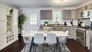 Une cuisine moderne avec un îlot en marbre, des chaises grises et des appareils électroménagers en acier inoxydable.